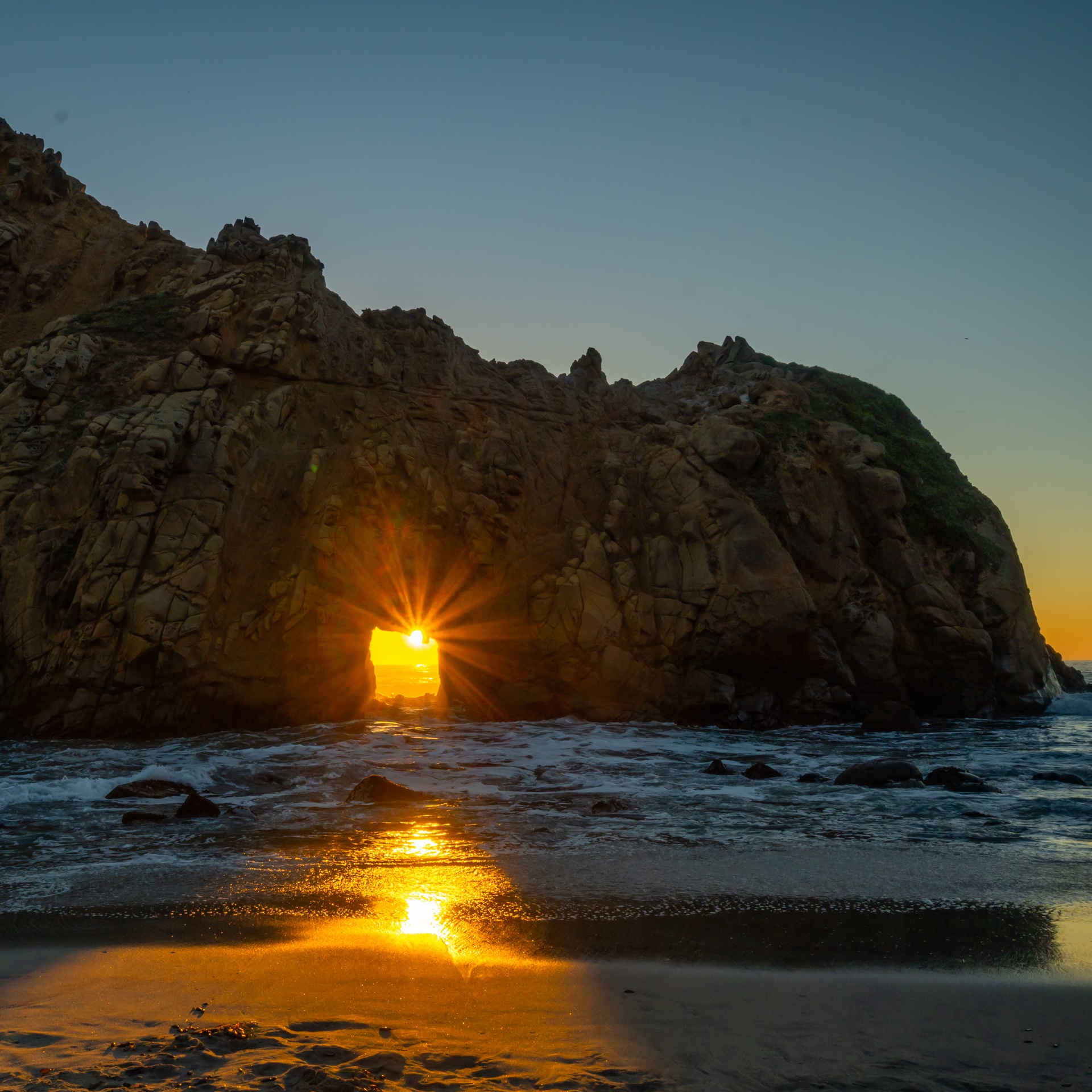Sunset starburst through the Pfeiffer Beach keyhole arch, Big Sur, California